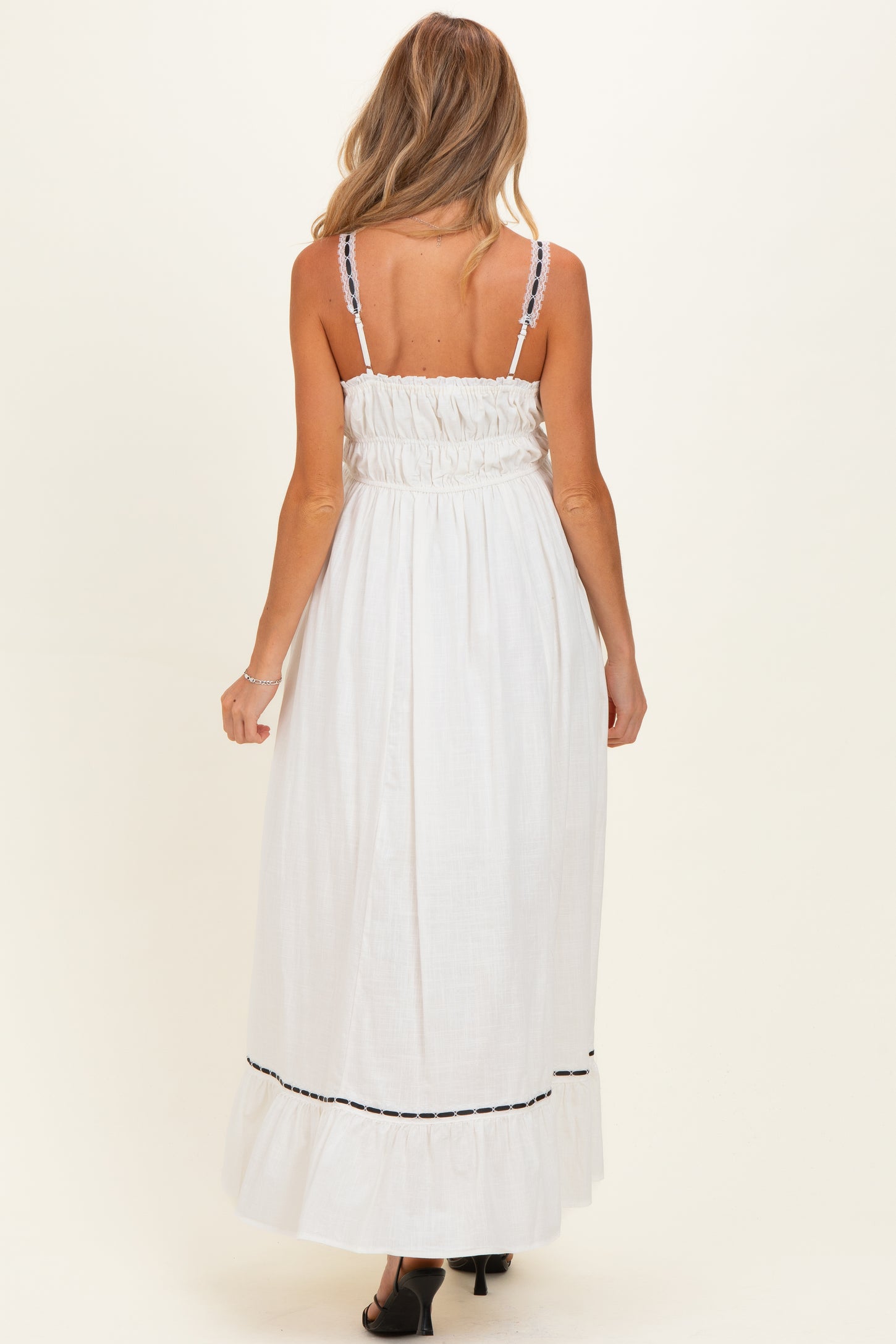 woman wearing a white maternity maxi dress with smocked back and black trim details