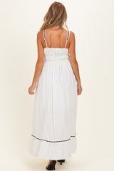 woman wearing a white maternity maxi dress with smocked back and black trim details