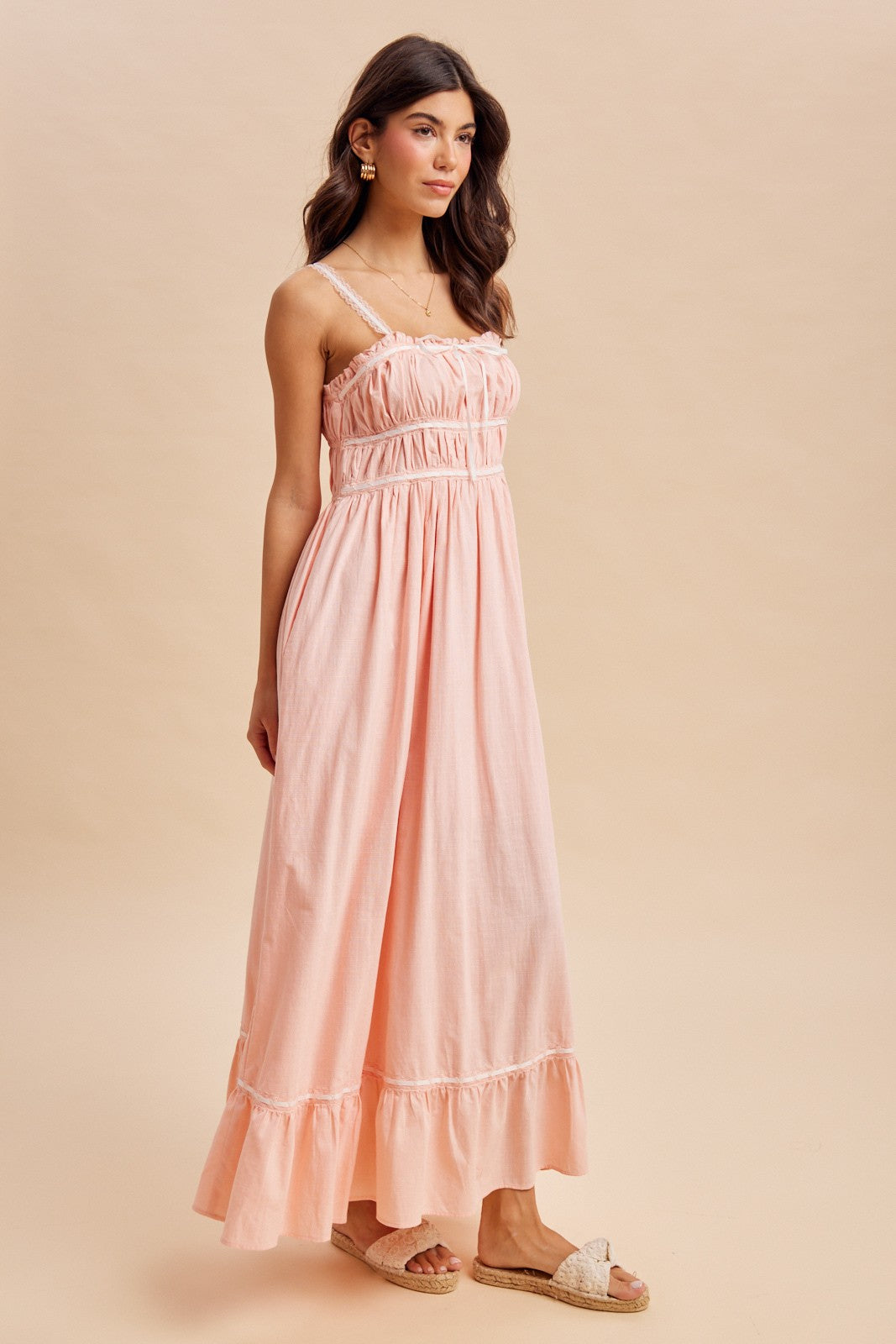 woman wearing a light pink maxi dress with spaghetti straps and ruffle hem details