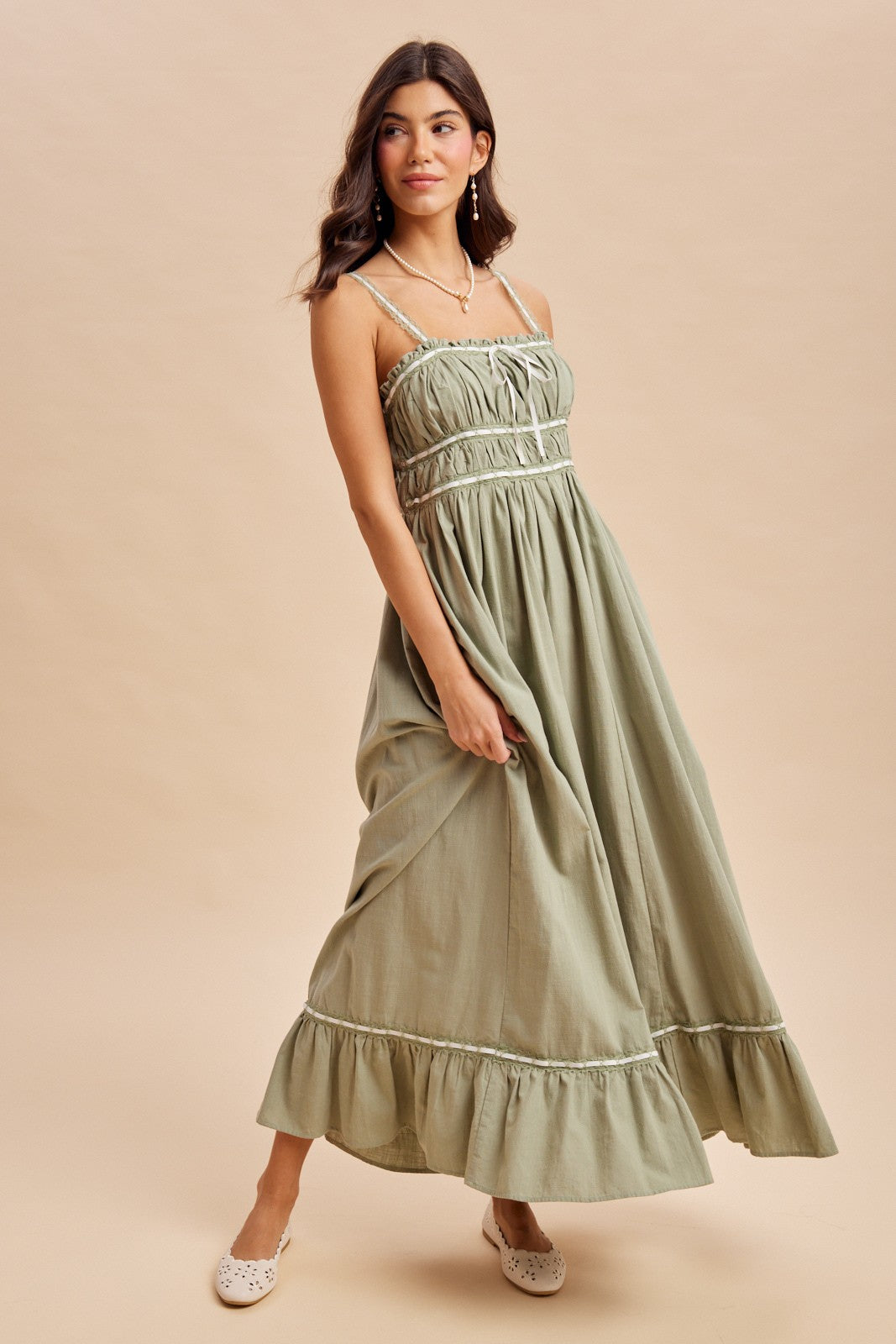 woman wearing an olive green maxi dress with a ruffled hem and spaghetti straps, styled on a light background