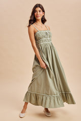woman wearing an olive green maxi dress with a ruffled hem and spaghetti straps, styled on a light background