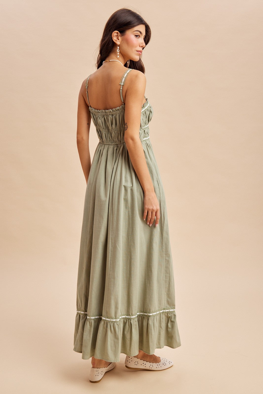woman wearing a green smocked back maxi dress with ruffled hem and thin straps, seen from the back