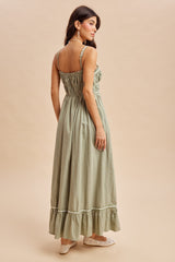 woman wearing a green smocked back maxi dress with ruffled hem and thin straps, seen from the back
