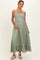 woman wearing a sage green maternity dress with a gathered bodice and ruffled hem, holding her baby bump