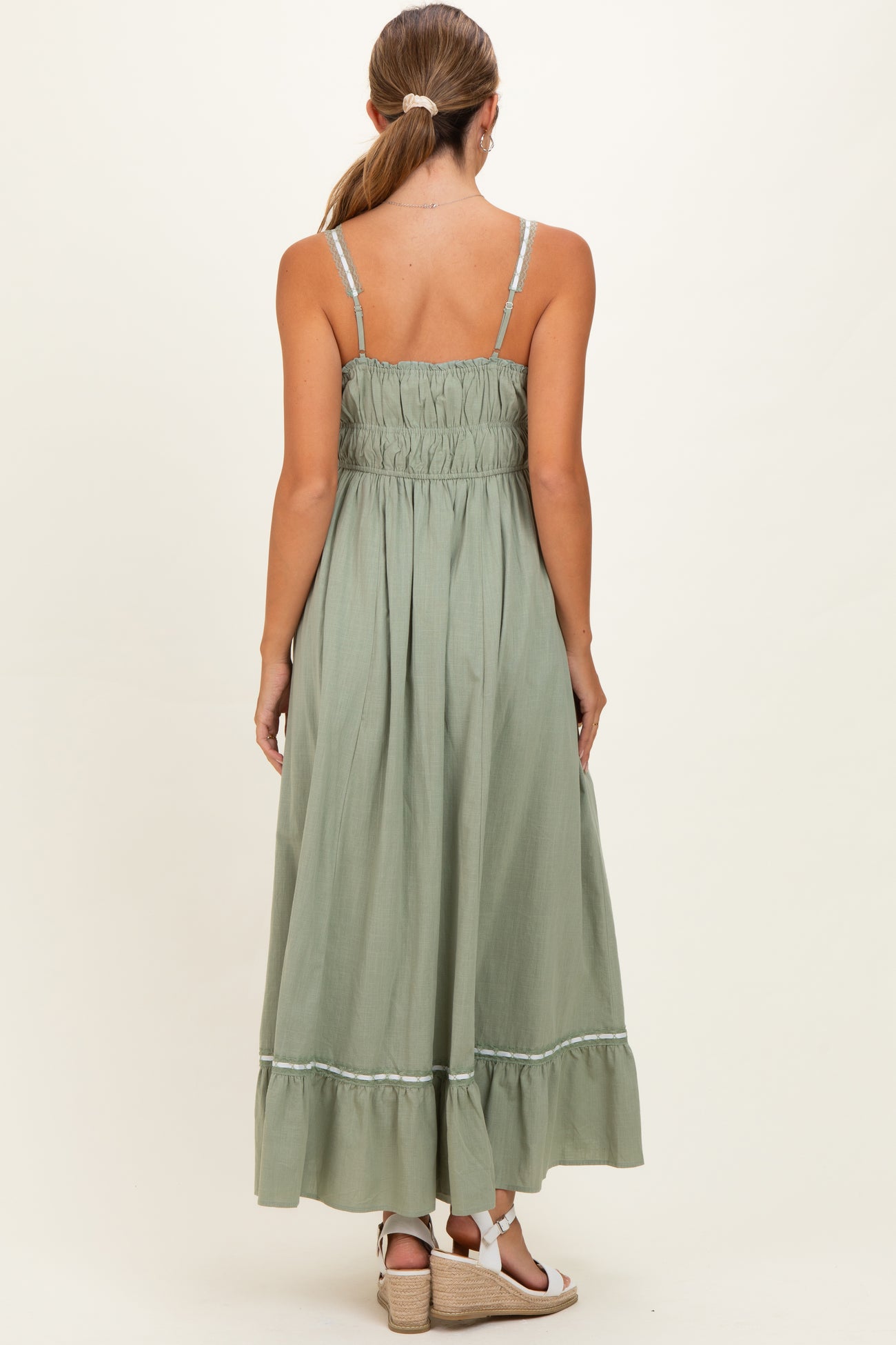 woman wearing a light green maternity maxi dress with a smocked back and ruffled hem