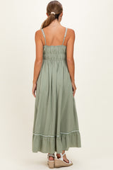 woman wearing a light green maternity maxi dress with a smocked back and ruffled hem