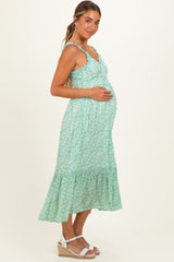 woman wearing a mint green floral maternity maxi dress and holding her baby bump