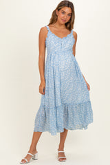woman wearing a light blue floral maternity dress with adjustable straps and a tiered hemline