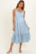 woman wearing a light blue floral maternity dress with adjustable straps and a tiered hemline