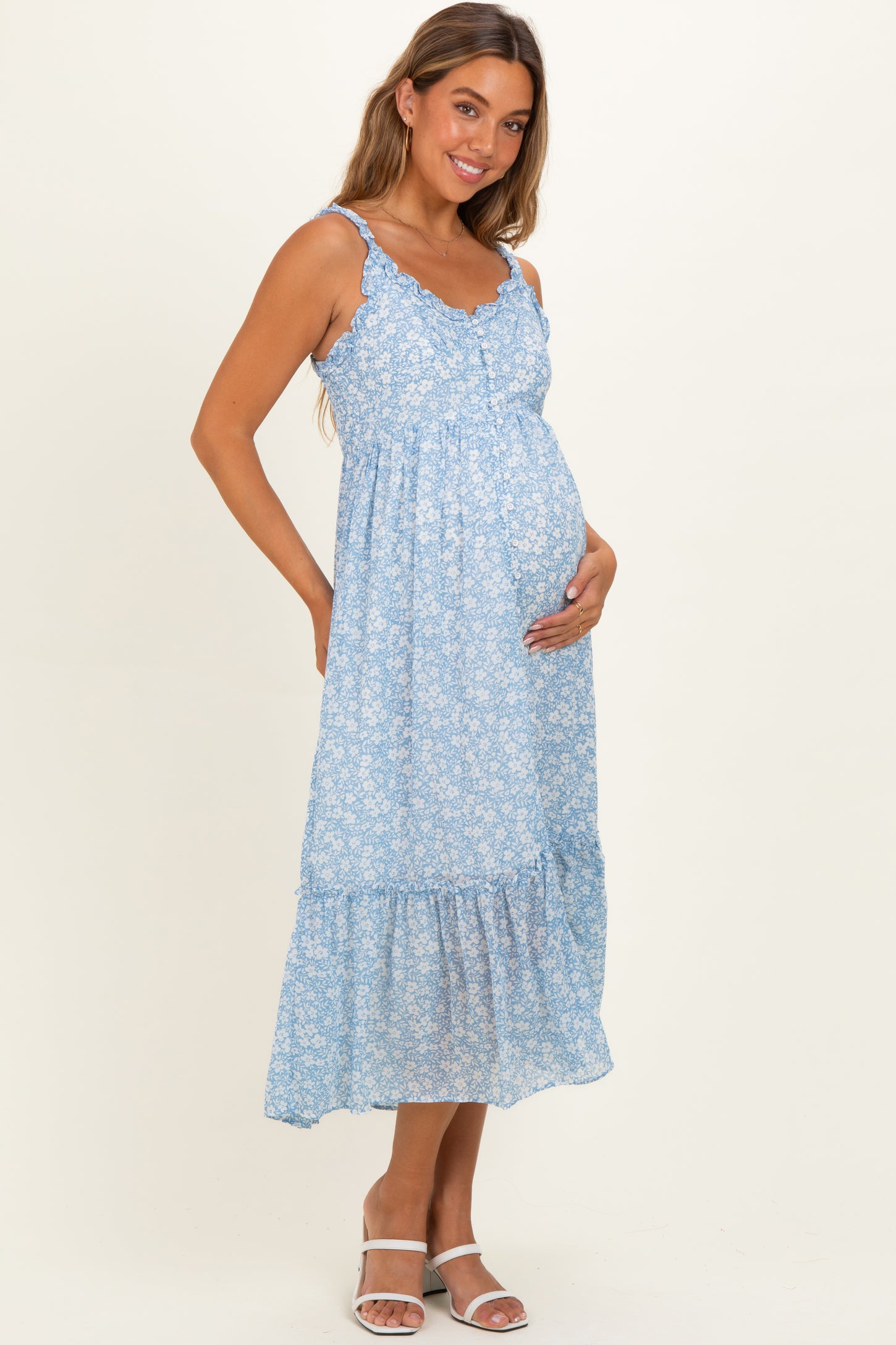woman wearing a light blue floral maternity maxi dress with ruffled hem and holding her baby bump