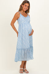 woman wearing a light blue floral maternity maxi dress with ruffled hem and holding her baby bump