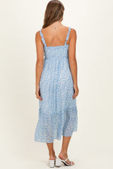 woman wearing a light blue floral maternity dress with adjustable straps and a tiered skirt, showing a baby bump