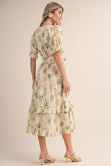 woman wearing a floral patterned midi dress with puff sleeves and ruffled hem, styled with yellow heeled sandals