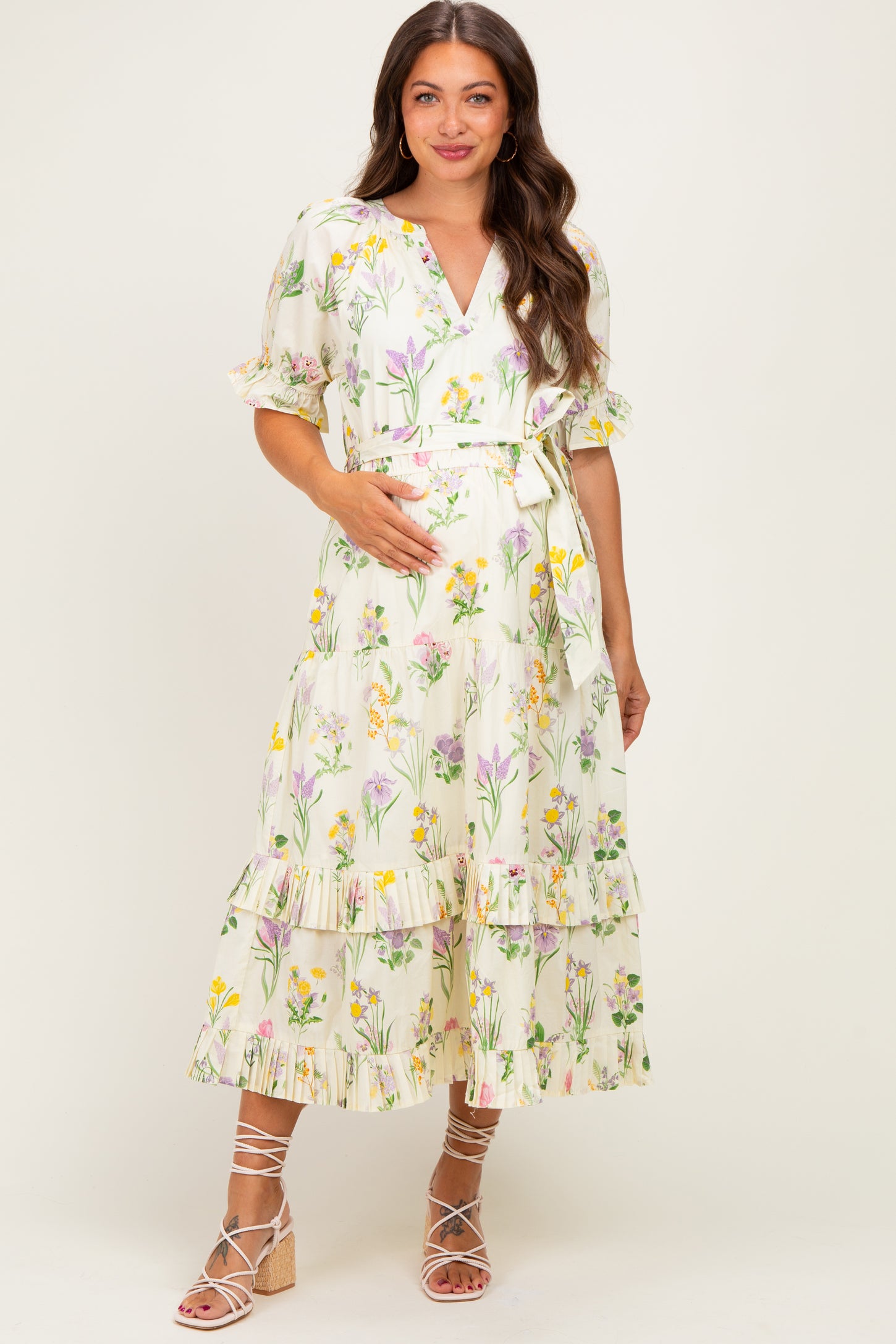 woman wearing a floral printed maternity dress with a tie waist and tiered ruffle hem, showing her baby bump