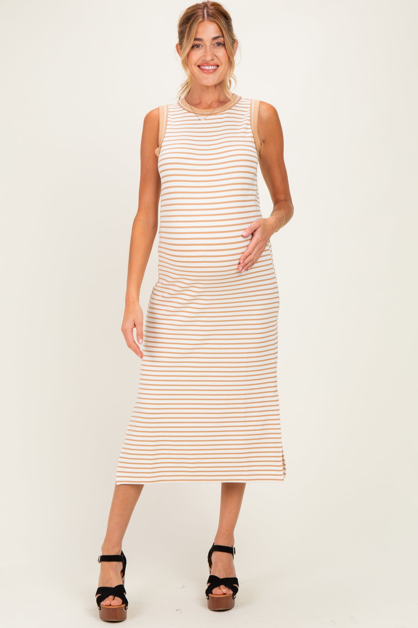 woman wearing a striped maternity dress with a fitted silhouette and a visible baby bump, standing and posing