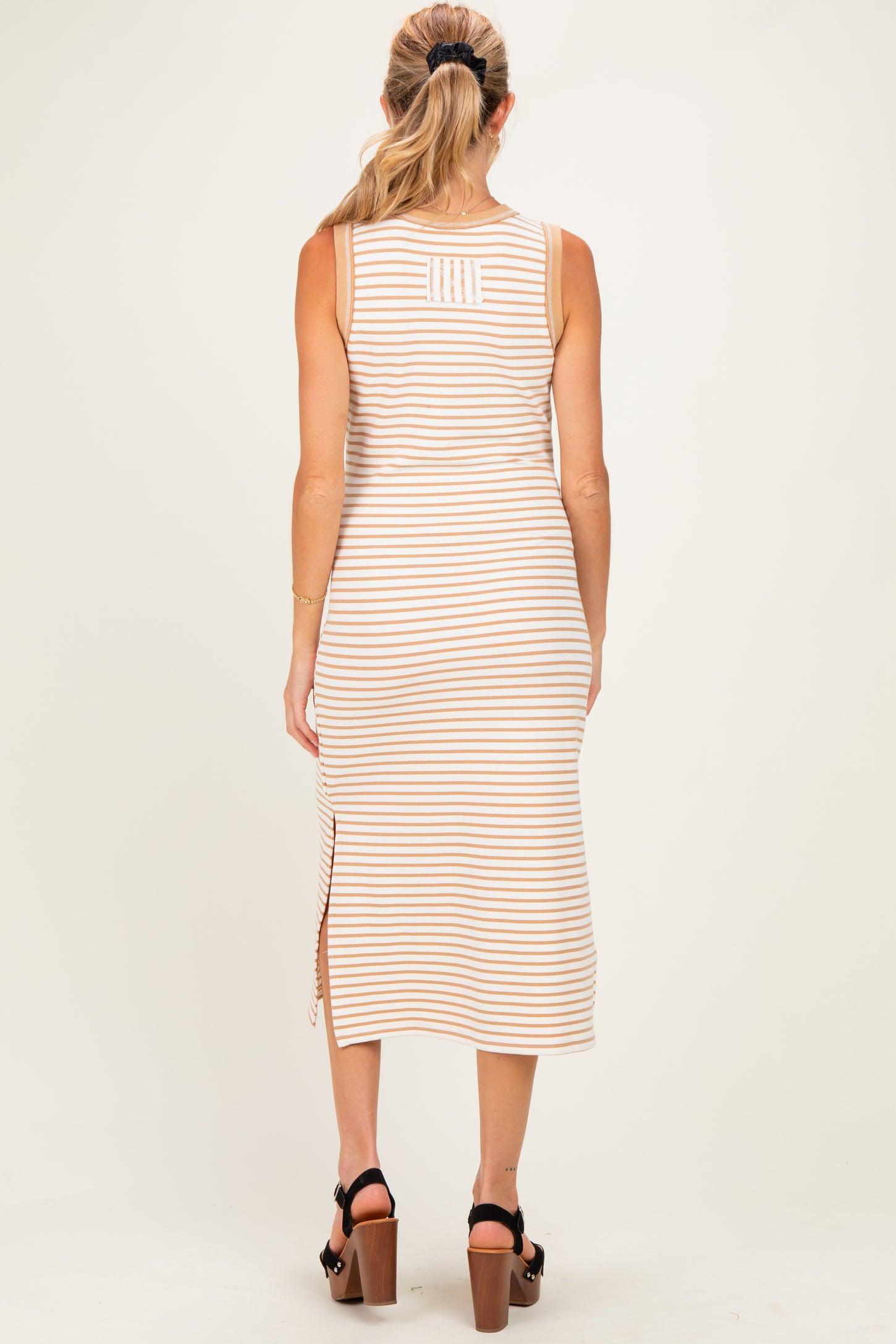 woman wearing a striped beige maternity dress with side slit and a fitted silhouette, shown from the back