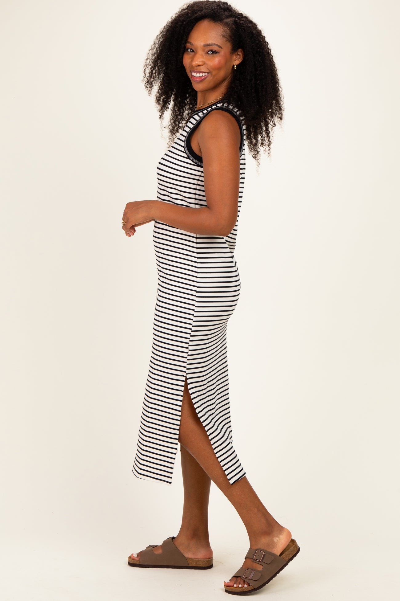 woman wearing a black and white striped midi dress with side slits and brown sandals