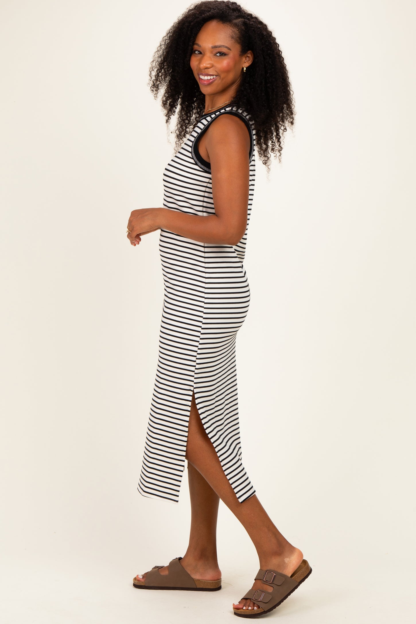 woman wearing a black and white striped midi dress with side slits and brown sandals