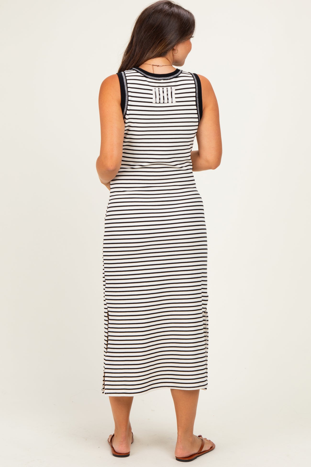 woman wearing a black and white striped maternity maxi dress with side slits and sleeveless design, showing a baby bump