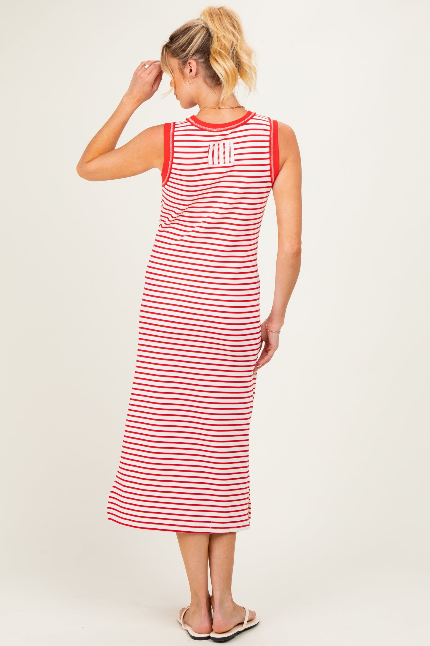 woman wearing a red and white striped maternity maxi dress with sleeveless design and back detail