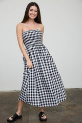 woman wearing a black and white gingham strapless maxi dress and black slide sandals