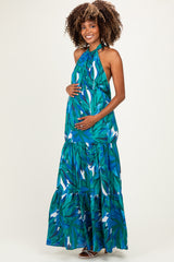 woman wearing a green tropical print maternity maxi dress and holding her baby bump