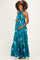 woman wearing a green tropical print maternity maxi dress and holding her baby bump
