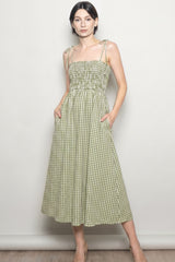 woman wearing a green and white gingham midi dress with adjustable tie straps and side pockets
