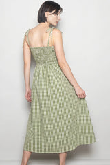 woman wearing a green and white gingham midi dress with adjustable tie straps and smocked bodice, seen from the back