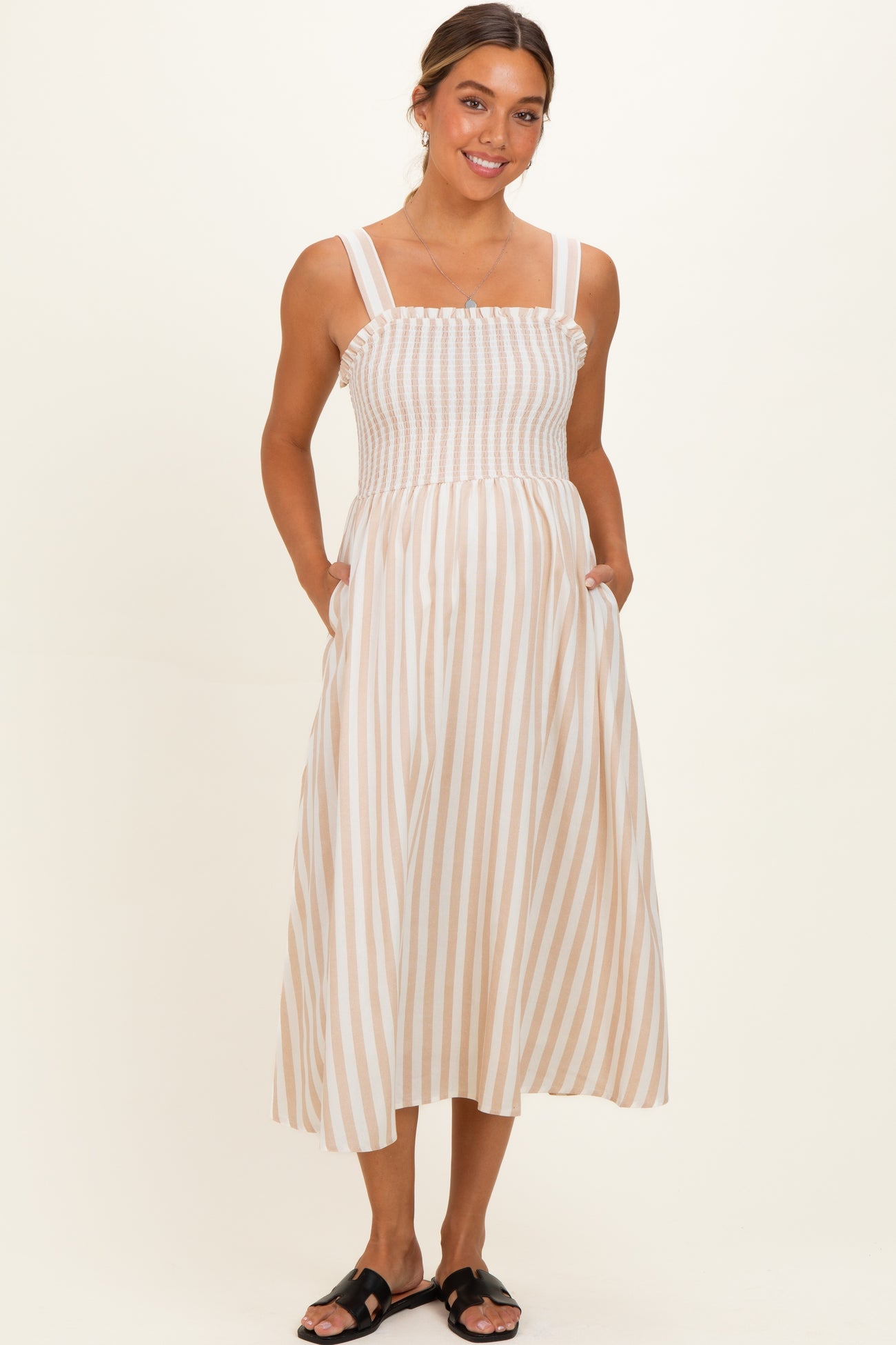 woman wearing a beige and white striped maternity maxi dress with a smocked bodice and pockets