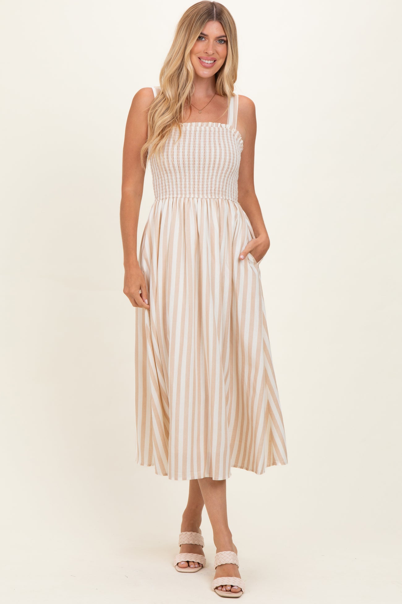 woman wearing a beige and white striped maxi dress with a smocked bodice and pockets