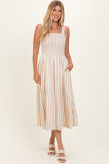 woman wearing a beige and white striped maxi dress with a smocked bodice and pockets
