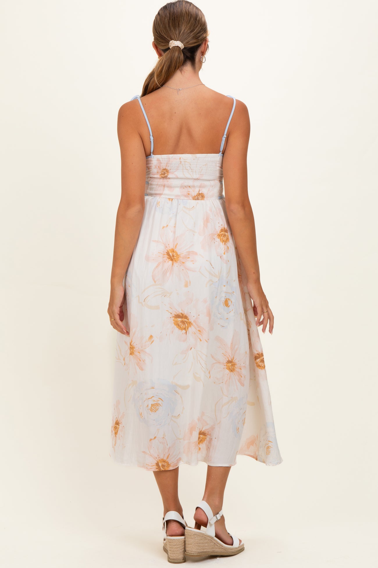 woman wearing a floral print maternity maxi dress with adjustable straps, showing a smocked back and flowing skirt