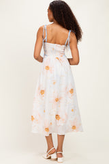 woman wearing a back view of a light blue floral midi dress with smocked bodice and adjustable straps