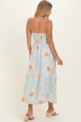 woman wearing a light blue floral maxi dress with tie shoulder straps and a fitted bodice, viewed from the back
