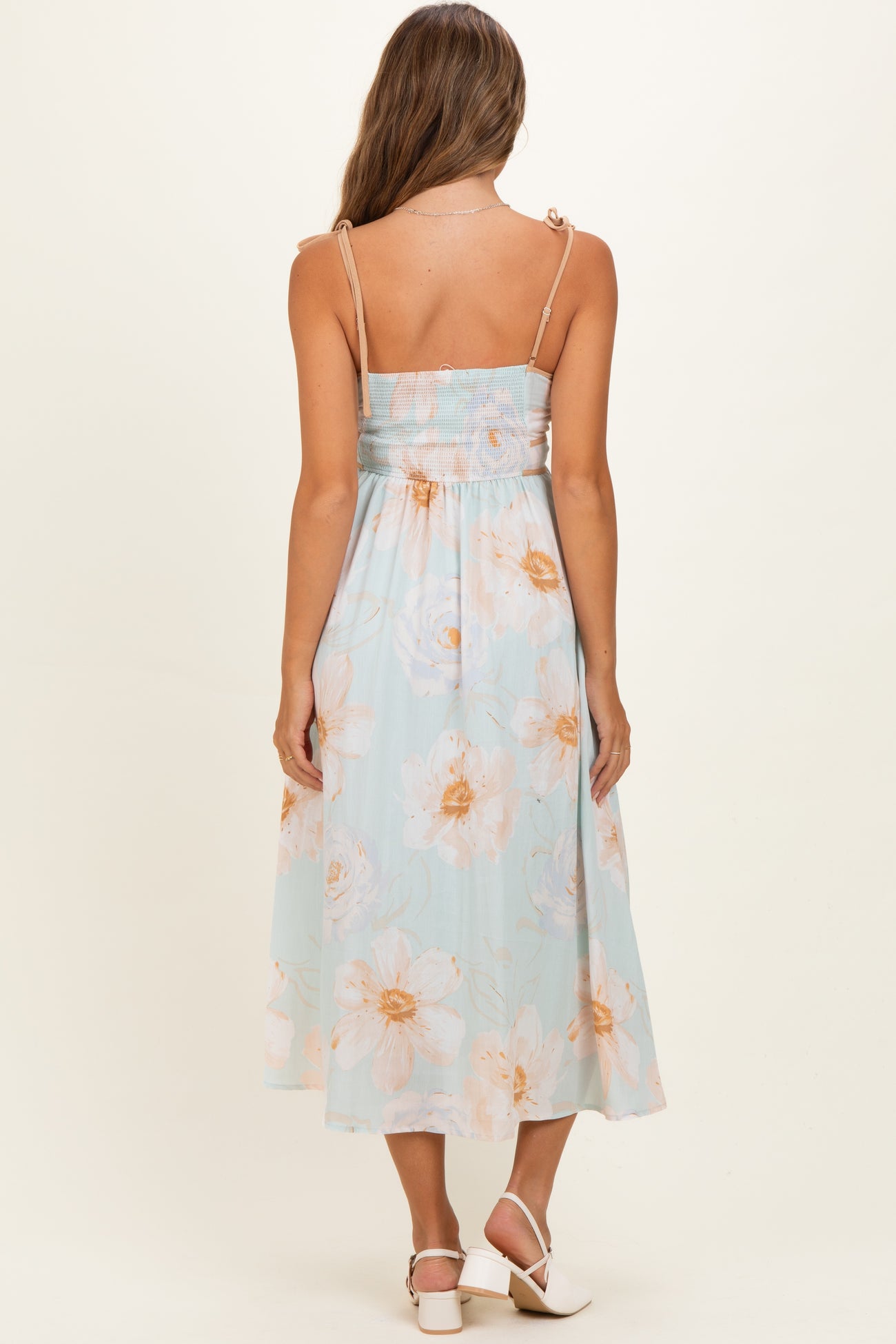 woman wearing a light blue floral maternity dress with adjustable straps and a smocked back