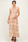 woman wearing a strapless beige floral maternity maxi dress and holding her baby bump