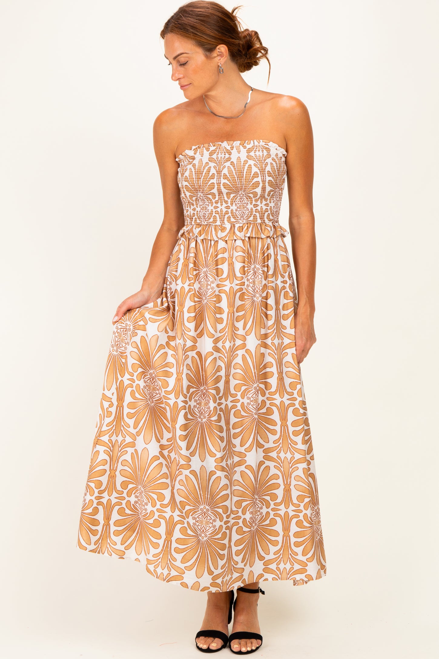 woman wearing a strapless bohemian floral maxi dress in beige and brown with a smocked bodice and flowy skirt