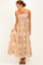 woman wearing a strapless bohemian floral maxi dress in beige and brown with a smocked bodice and flowy skirt