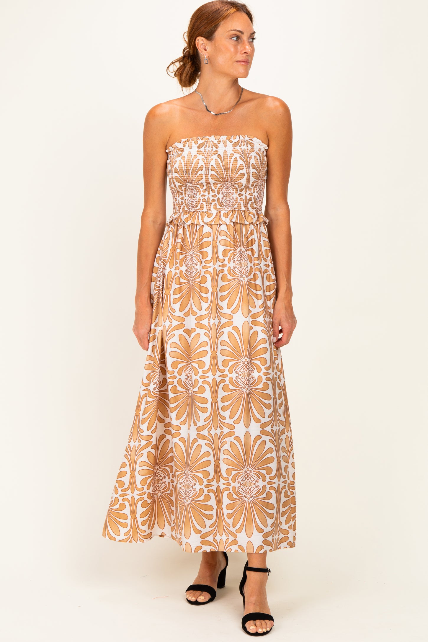 woman wearing a strapless maxi dress with a floral print in warm tones and a fitted bodice