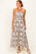 woman wearing a strapless maxi dress with a floral print in shades of brown and beige.