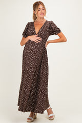 woman wearing a brown polka dot maternity maxi dress and posing with her baby bump visible