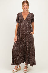 woman wearing a brown polka dot maternity maxi dress with short puffy sleeves and pockets, displaying her baby bump