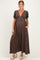 woman wearing a brown polka dot maternity maxi dress with short puffy sleeves and pockets, displaying her baby bump