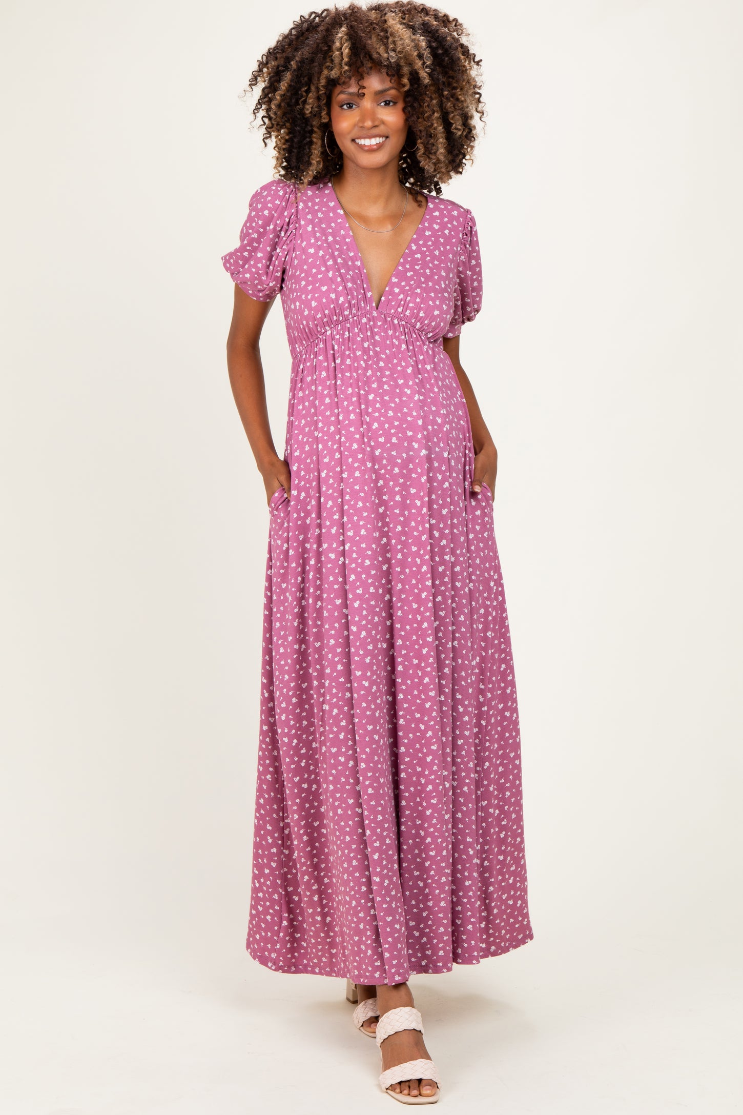 woman wearing a purple polka dot maternity maxi dress with short puff sleeves and pockets, showcasing her baby bump
