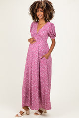 woman wearing a pink polka dot maternity maxi dress, with puff sleeves and pockets, showing her baby bump