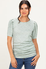woman wearing a green floral short sleeve top with puff sleeves and ruched detailing, paired with denim jeans