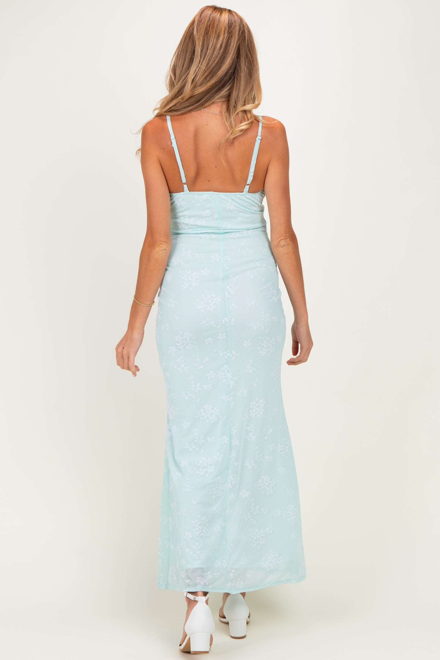 woman wearing a light blue floral maternity maxi dress with a fitted bodice and adjustable straps, showing a baby bump