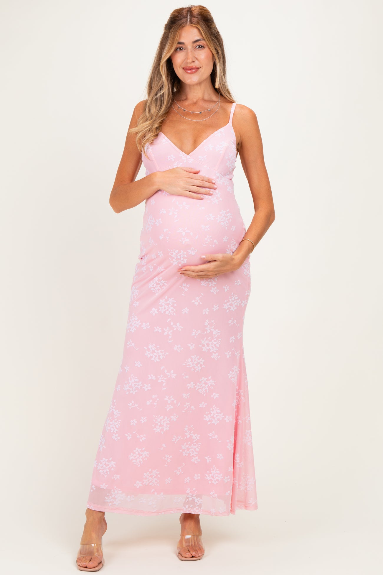 woman wearing a pink floral maternity maxi dress and holding her baby bump
