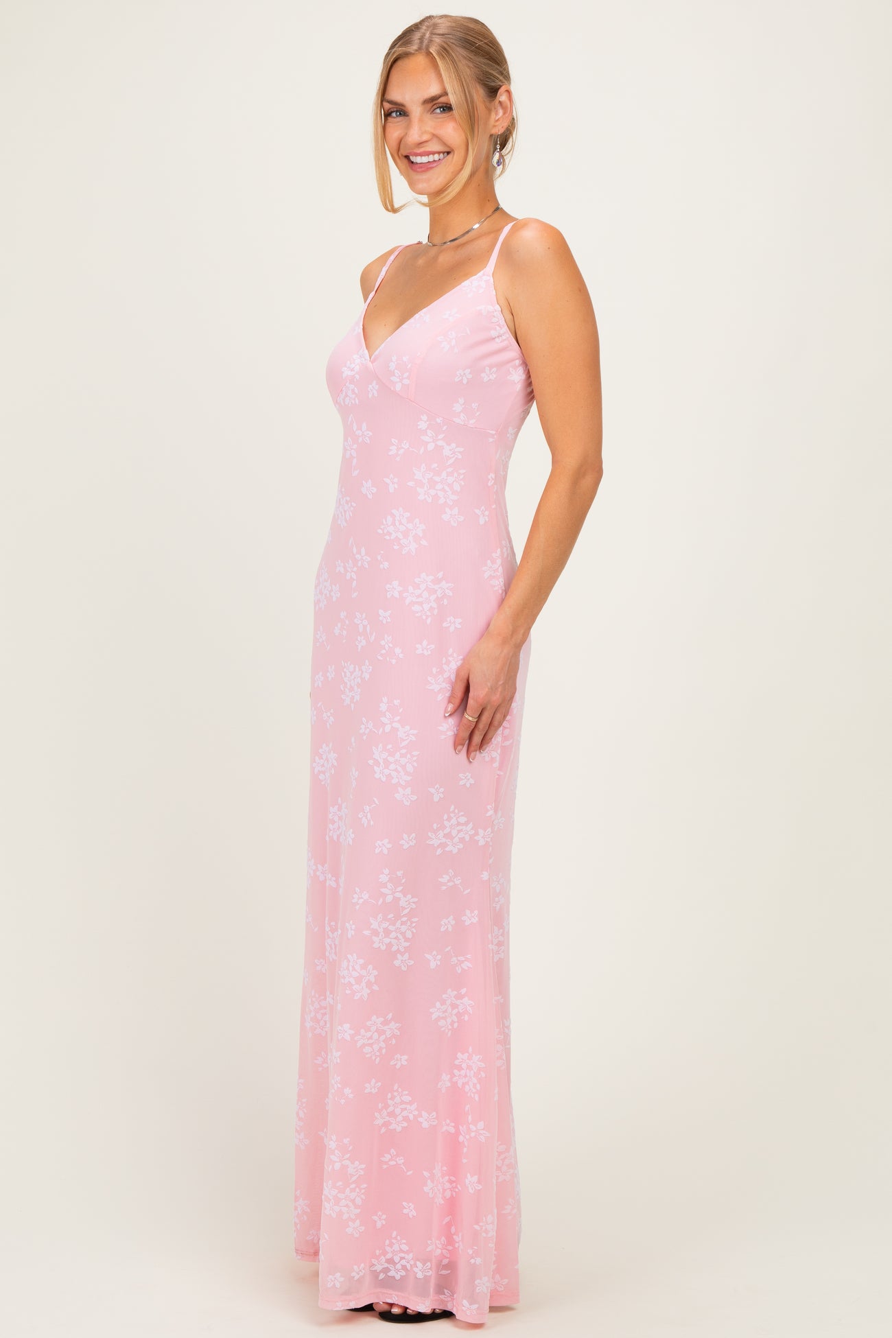 woman wearing a pink floral long dress with spaghetti straps and a fitted silhouette